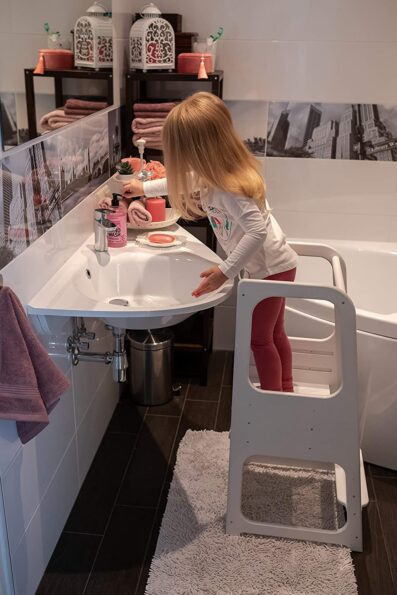 petite fille sur une tour Montessori dans la salle de bain